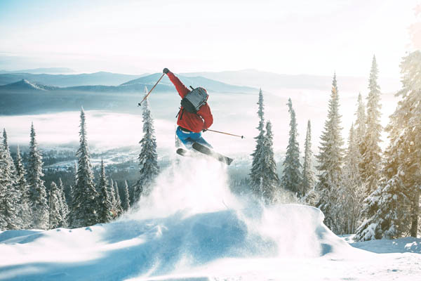 Skifahrer springt in die Luft auf einer schneebedeckten Piste